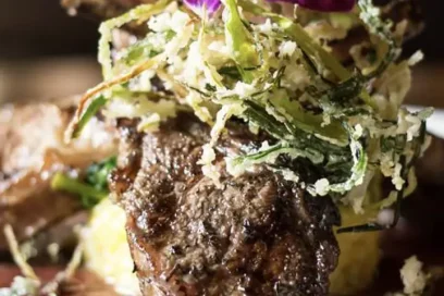 Grilled meat topped with shaved cheese and greens